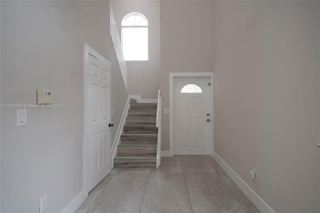 entryway with light tile patterned flooring and a towering ceiling