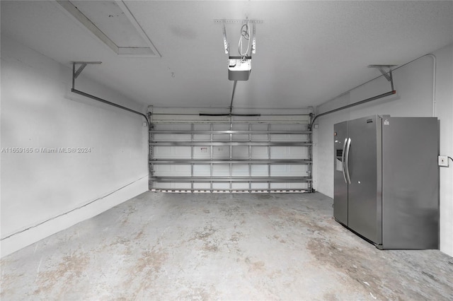 garage with stainless steel refrigerator with ice dispenser and a garage door opener