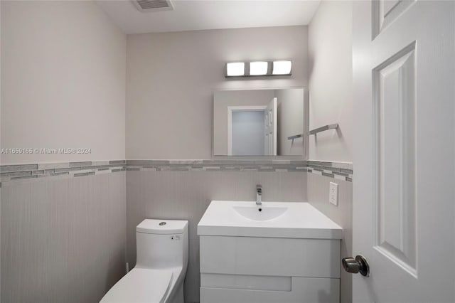 bathroom with tile walls, vanity, and toilet