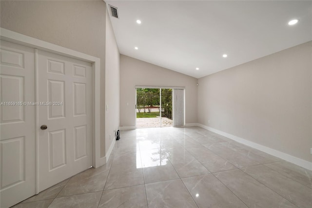 tiled empty room featuring lofted ceiling