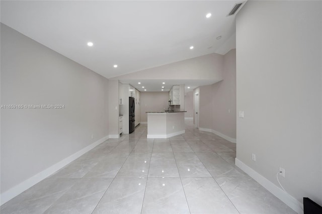 hallway with lofted ceiling and light tile patterned flooring