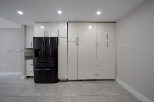 kitchen featuring white cabinetry, black fridge with ice dispenser, and stone counters