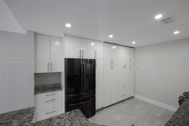 kitchen with white cabinets, stainless steel refrigerator with ice dispenser, dark stone counters, and light tile patterned flooring