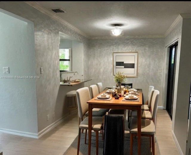 dining area with light wood-type flooring and ornamental molding