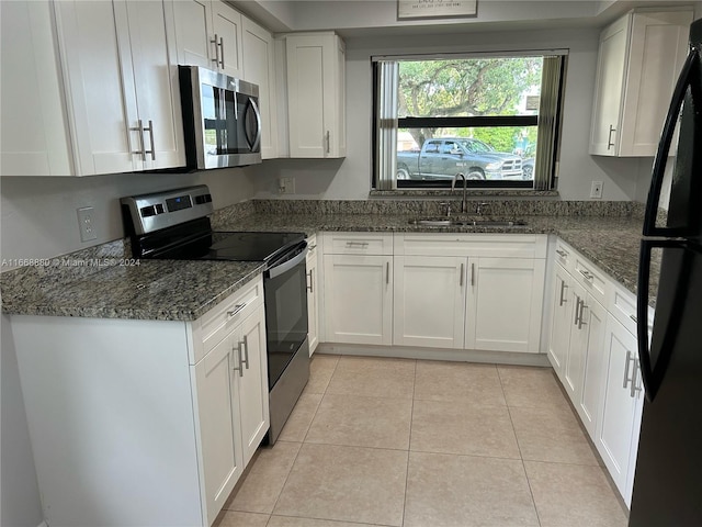 kitchen featuring light tile patterned floors, sink, white cabinetry, appliances with stainless steel finishes, and dark stone countertops