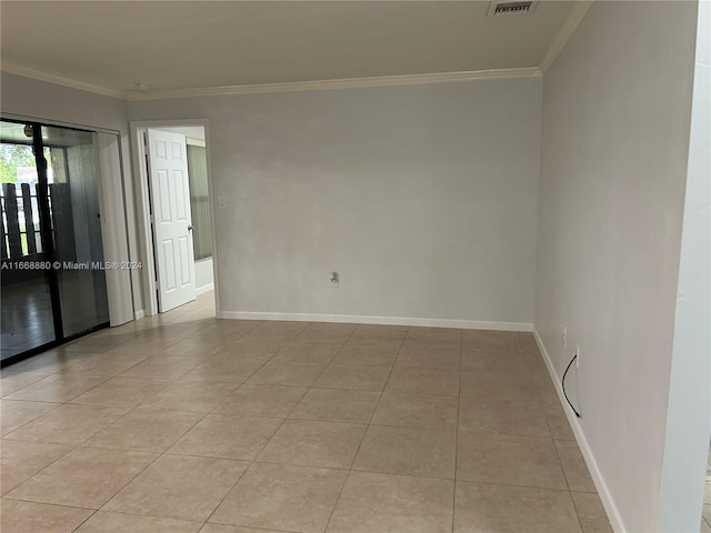 empty room featuring light tile patterned flooring and crown molding