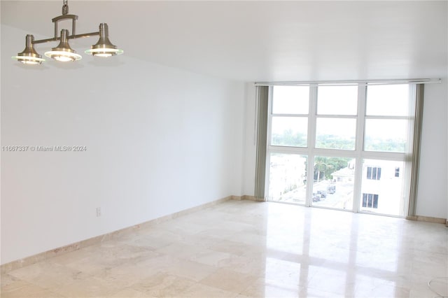 tiled spare room with expansive windows and a notable chandelier