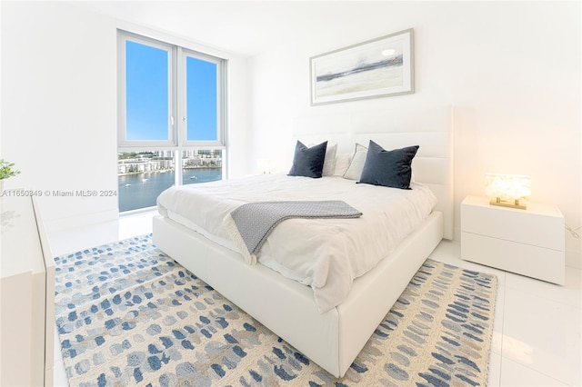 bedroom with tile patterned flooring, a water view, and access to exterior