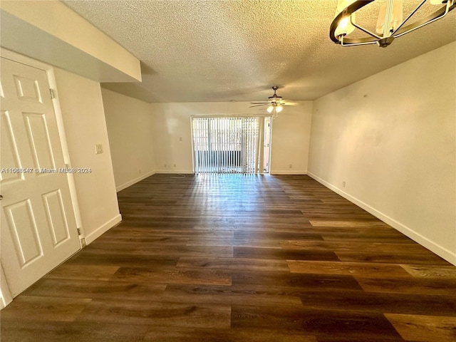 empty room with a textured ceiling, ceiling fan with notable chandelier, and dark wood-type flooring