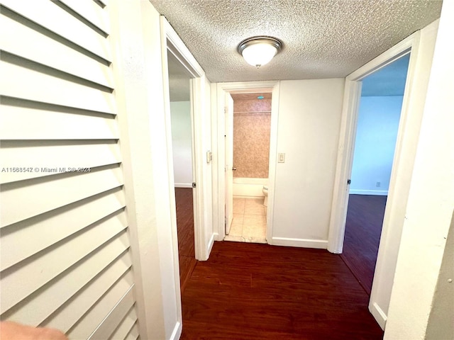 hall featuring a textured ceiling and dark wood-type flooring