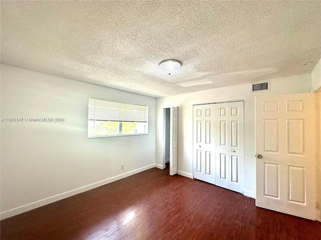 unfurnished bedroom with a textured ceiling and dark hardwood / wood-style floors