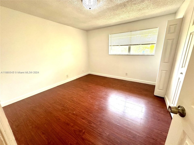 unfurnished bedroom with a textured ceiling and dark hardwood / wood-style flooring