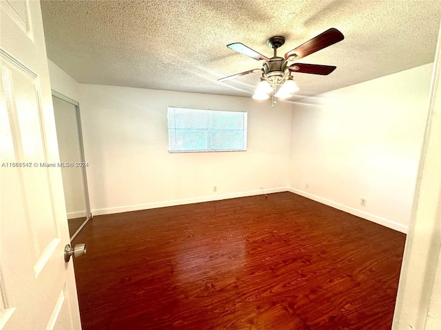 unfurnished room featuring ceiling fan, dark wood-type flooring, and a textured ceiling