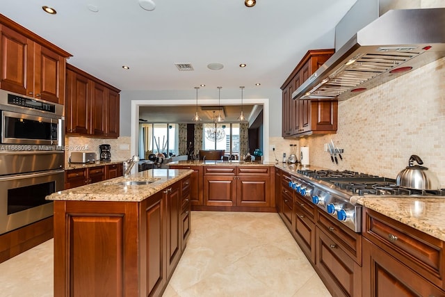 kitchen with pendant lighting, kitchen peninsula, wall chimney exhaust hood, backsplash, and appliances with stainless steel finishes