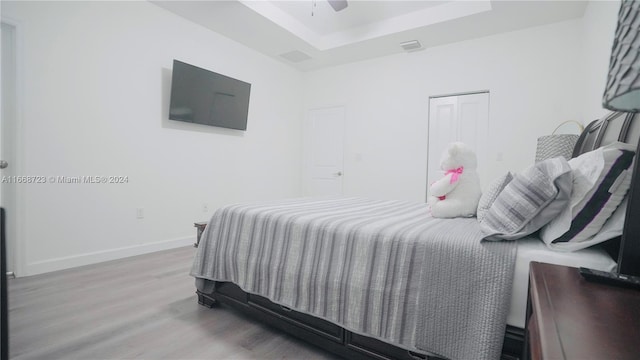 bedroom featuring a raised ceiling, hardwood / wood-style floors, and ceiling fan