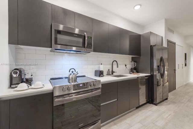 kitchen featuring tasteful backsplash, sink, light hardwood / wood-style flooring, stainless steel appliances, and dark brown cabinetry