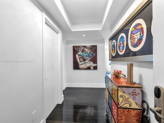 corridor featuring a tray ceiling and dark hardwood / wood-style flooring