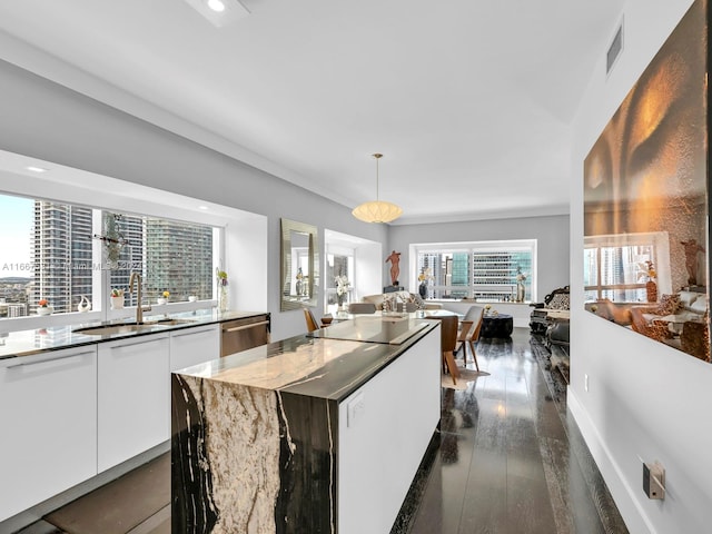 kitchen with white cabinetry, a kitchen island, dark hardwood / wood-style flooring, decorative light fixtures, and sink