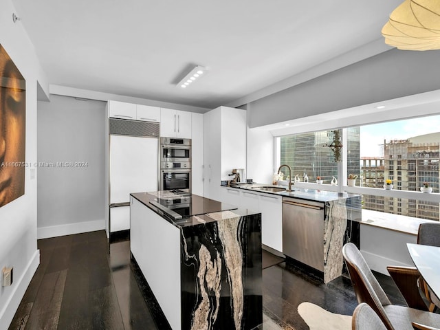 kitchen featuring appliances with stainless steel finishes, white cabinets, dark hardwood / wood-style flooring, a center island, and sink