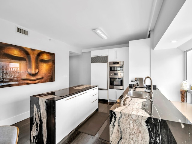 kitchen featuring paneled refrigerator, white cabinetry, stainless steel double oven, and dark hardwood / wood-style flooring