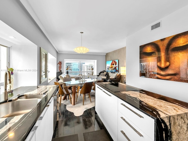 kitchen with white cabinetry, dark hardwood / wood-style flooring, sink, and decorative light fixtures