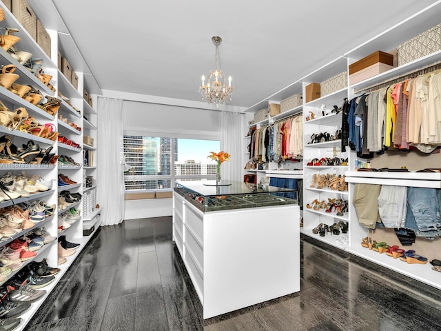 spacious closet featuring an inviting chandelier and dark hardwood / wood-style floors