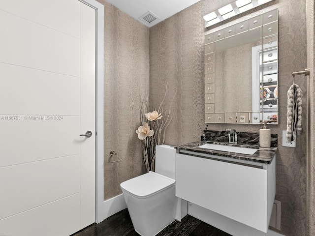 bathroom with wood-type flooring, vanity, and toilet