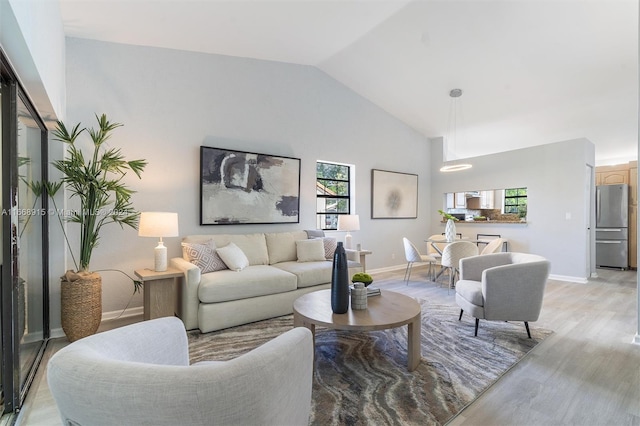 living room with light wood-type flooring and high vaulted ceiling