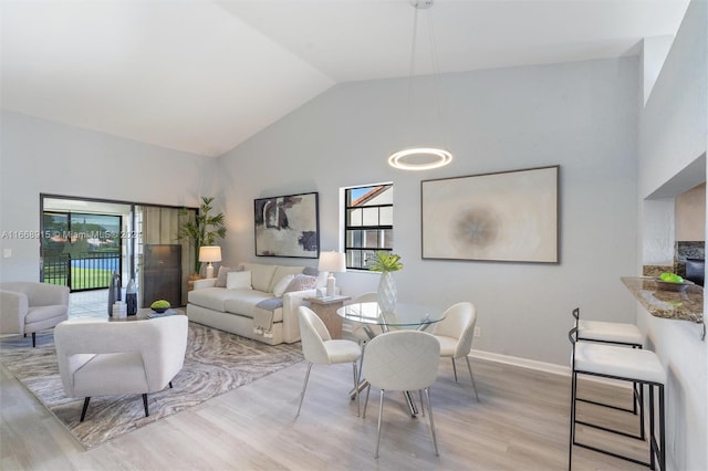 dining area featuring light hardwood / wood-style flooring, a wealth of natural light, and high vaulted ceiling