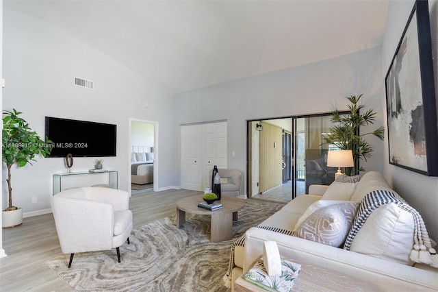 living room with light wood-type flooring and high vaulted ceiling