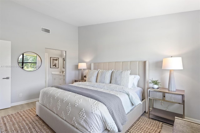 bedroom featuring light hardwood / wood-style flooring and ensuite bath