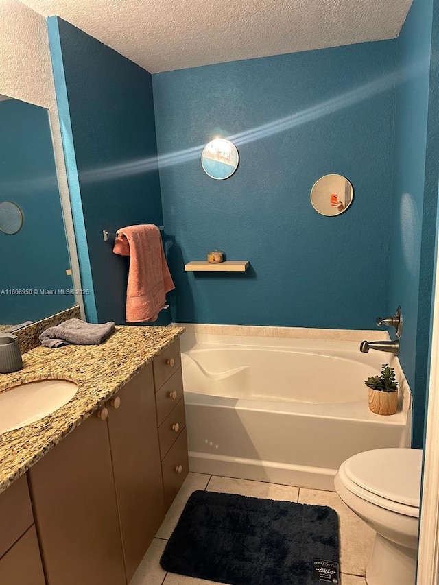 bathroom with tile patterned floors, a bathtub, a textured ceiling, and vanity