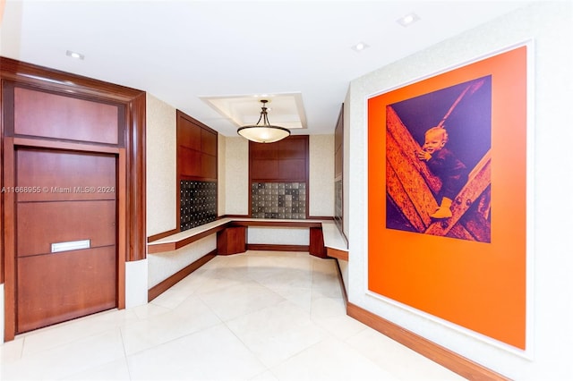 hallway featuring baseboards, mail area, and light tile patterned floors