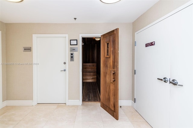 hall featuring baseboards and light tile patterned floors