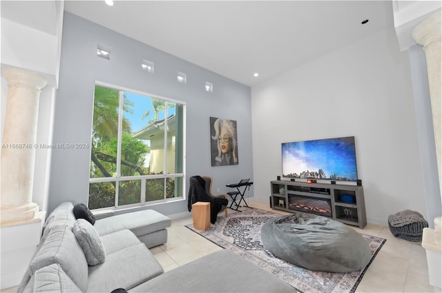 living room featuring decorative columns, a towering ceiling, light tile patterned floors, and a wealth of natural light