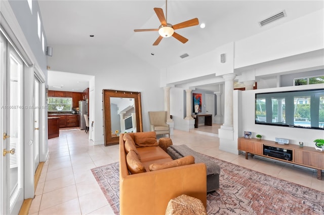 tiled living room with high vaulted ceiling, a wealth of natural light, ceiling fan, and ornate columns