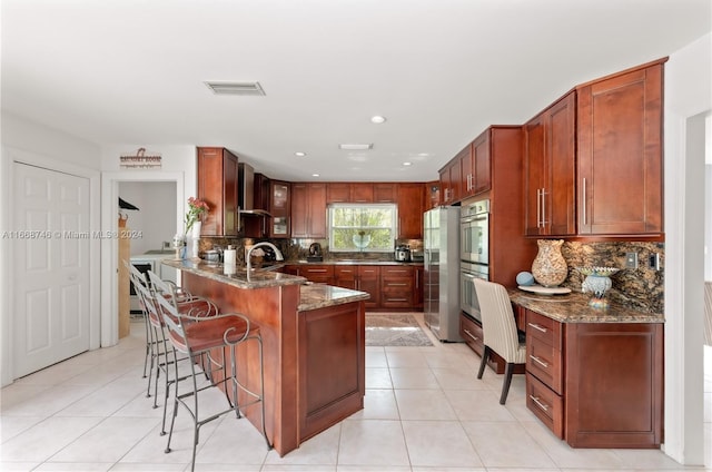 kitchen featuring a breakfast bar, dark stone counters, sink, wall chimney exhaust hood, and backsplash