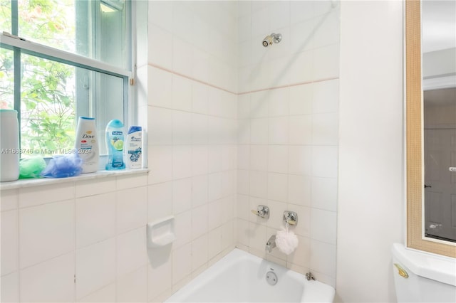 bathroom with tiled shower / bath combo and toilet