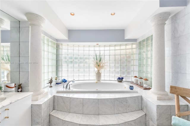 bathroom with tile walls, tiled bath, and ornate columns