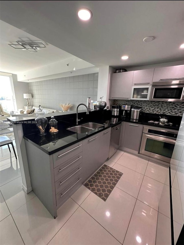 kitchen featuring light tile patterned flooring, sink, gray cabinetry, stainless steel appliances, and backsplash