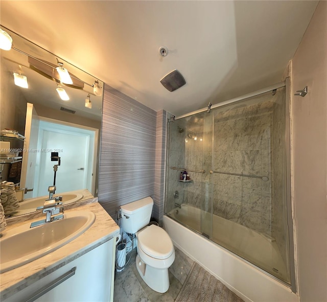 full bathroom with enclosed tub / shower combo, vanity, and toilet