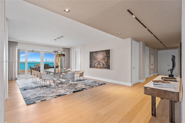 dining area with light wood-type flooring and a notable chandelier