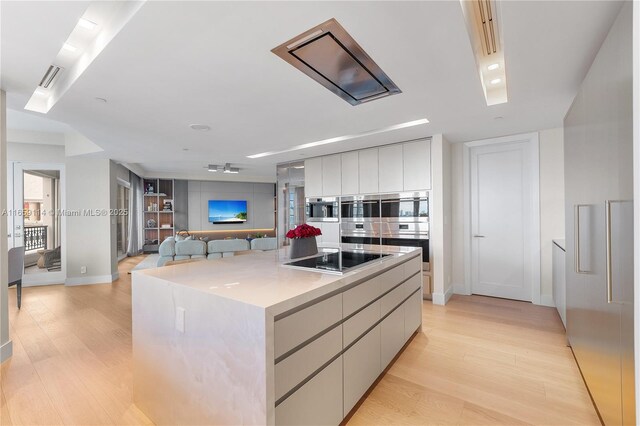 kitchen featuring a kitchen island, black electric stovetop, light wood-type flooring, and stainless steel double oven