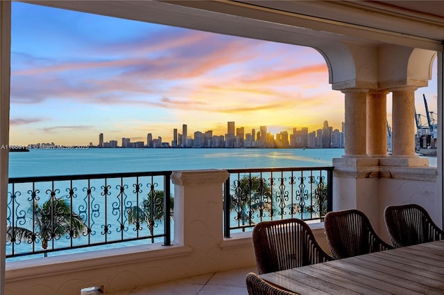 balcony at dusk featuring a water view