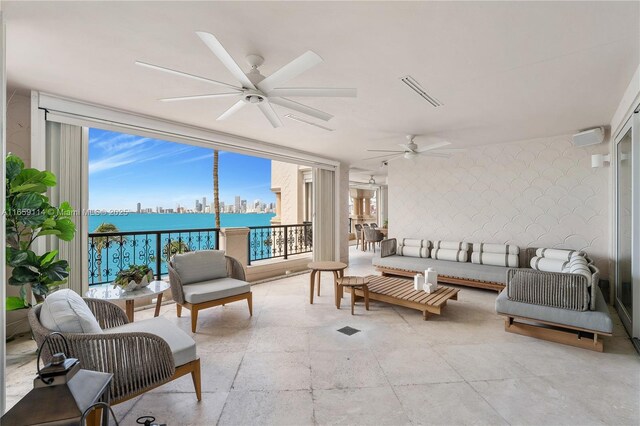 sunroom with ceiling fan and a water view