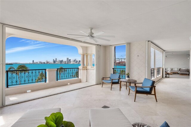 patio terrace at dusk featuring a balcony, a water view, and ceiling fan