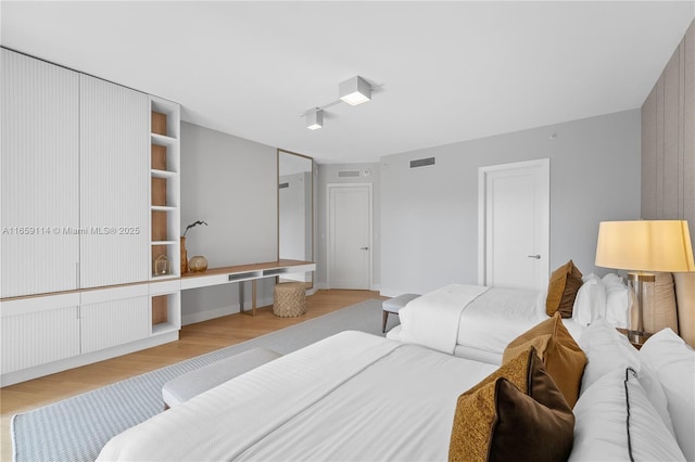 bedroom featuring rail lighting and light hardwood / wood-style flooring