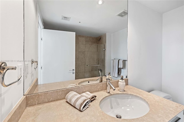 bathroom featuring vanity, a tile shower, and toilet