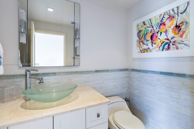 bathroom with a tile shower, vanity, and toilet