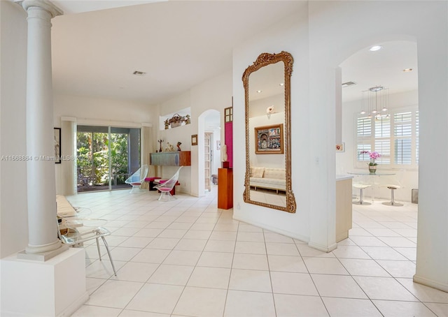 hall with light tile patterned floors and decorative columns